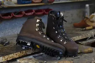 Braune Bergschuhe mit Grödeln auf einer Werkbank in der Werkstatt