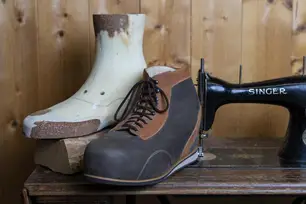 Orthopädischer Maßschuh neben dem zugehörigen Leisten aus Holz